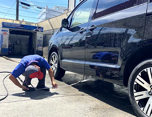 スタッフが手洗い洗車で予備洗いをしている写真